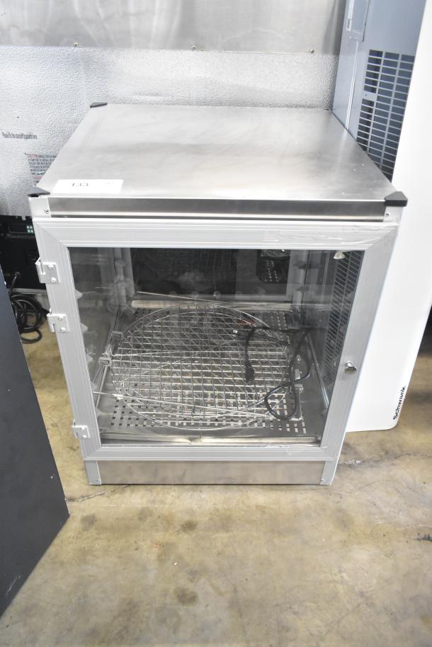 Brand new countertop warming display case, 115V, 1 phase, with minor scratches. Features glass door and metal racks.