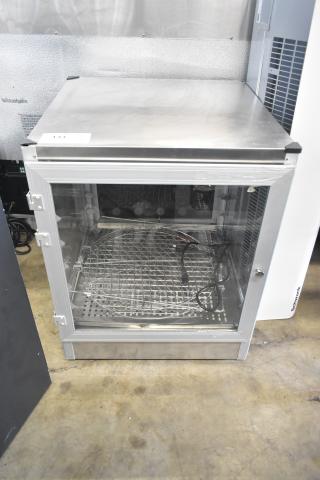 Brand new countertop warming display case, 115V, 1 phase, with minor scratches. Features glass door and metal racks.