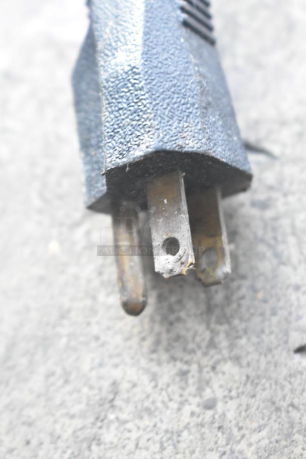 A close-up of a worn electrical plug with visible corrosion on the prongs.