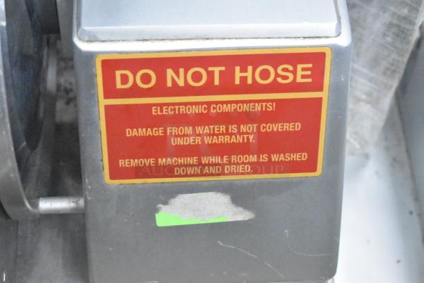 Bizerba commercial meat slicer stacker with a warning label on electronics about water damage. 115V, 1 phase.