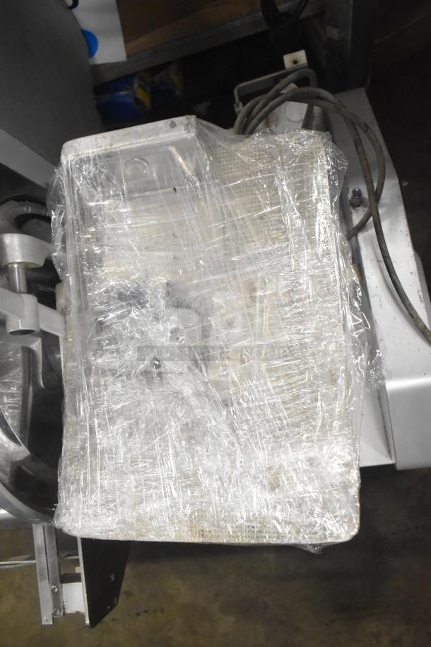 Bizerba Commercial Meat Slicer Stacker, 115V, 1 Phase, packaged in protective wrap, visible wires, countertop design.