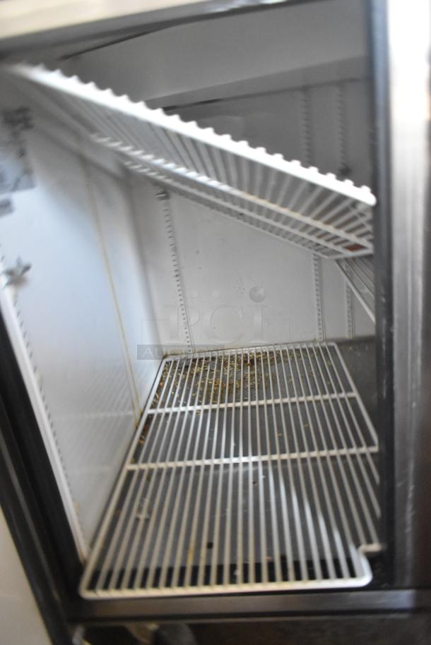 True TPP-60 commercial pizza prep table interior with wire shelving. Features: 115 volts, 1 phase, on commercial casters.