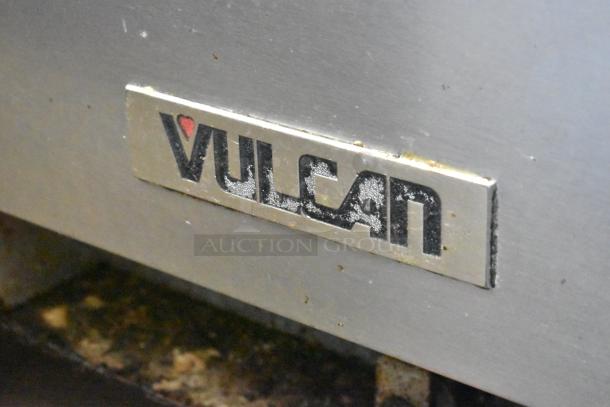 Vulcan commercial gas range logo. Features include four burners, flat top griddle, oven on casters, missing two grates.