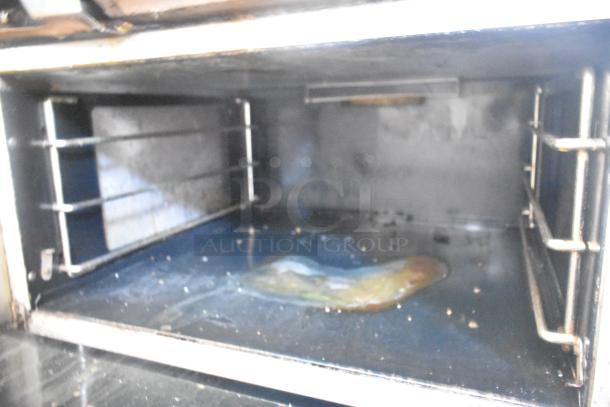 Vulcan commercial gas range interior showing wear, missing two grates, with flat top griddle and oven on casters.