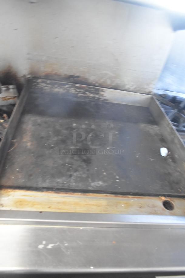 ThermaTek commercial gas-powered range, featuring a 6-burner stove, flat top griddle, and two ovens. Signs of use visible.