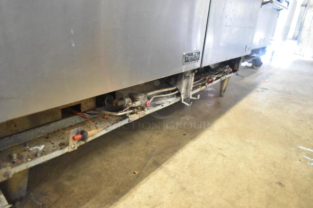 ThermaTek commercial gas range with 6 burners, flat top griddle, 2 ovens. Metal housing, visible wear. Brand tag shown.