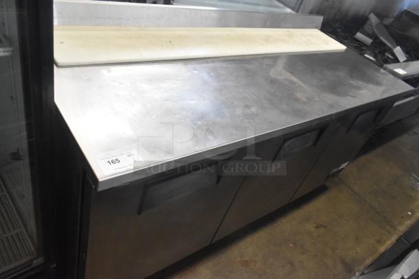 True TWT-72 commercial 3-door worktop cooler on casters. Features stainless steel surface, cutting board, and 115V power.