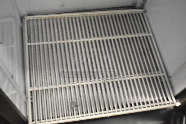 True GDM-12 single door cooler interior shelf. White wire rack, some wear visible. Commercial unit.