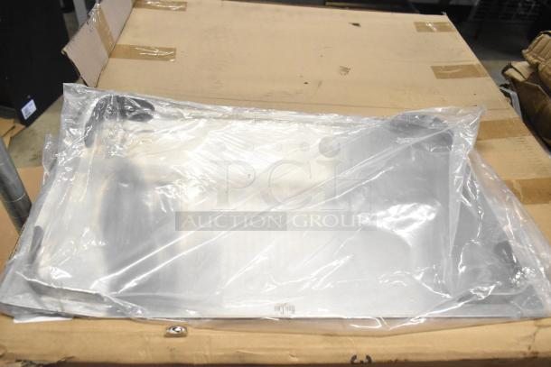 New scratch and dent metal rack wrapped in plastic, resting on a cardboard box. Rugged yet unused condition.