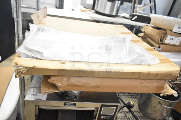 Three metal racks, brand new with scratch and dent, in original packaging. Labels indicate auction lot number 193.