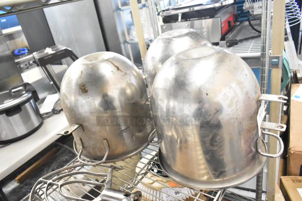 Stainless steel mixing bowls and paddle attachments, used, slight wear, on metal shelving.