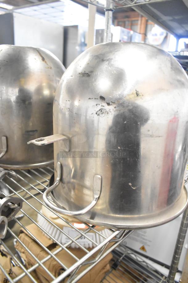 Stainless steel mixing bowls and paddle attachments on metal shelf, showing wear.