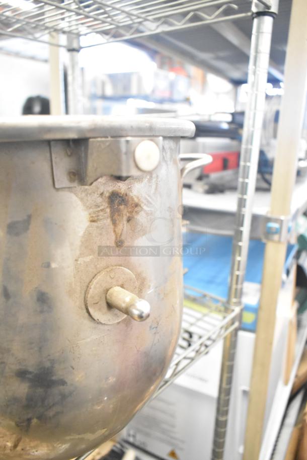 Vintage metal mixing bowl with handle, lightly tarnished, industrial setting. Part of 5-item auction lot, includes paddle attachments.