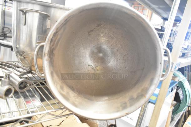 Five kitchen items including three stainless steel mixing bowls and two metal paddle attachments on a wire rack. Used condition.