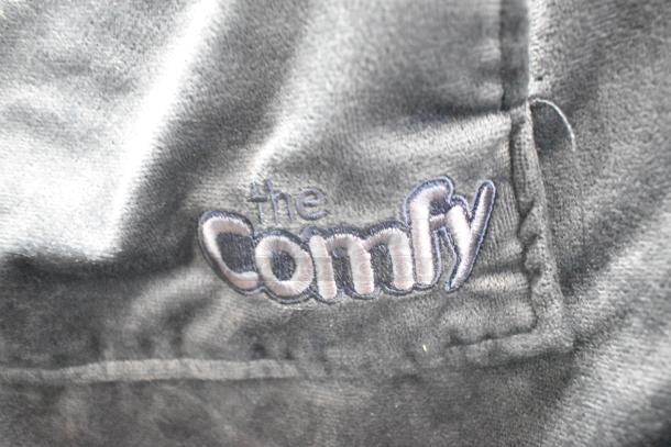 Alt text: Close-up of dark fabric with "the Comfy" embroidered in white and blue stitching.