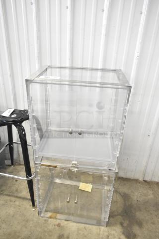 2 clear poly countertop cabinets, stackable design, transparent doors with knobs, slight wear visible, ideal for display.