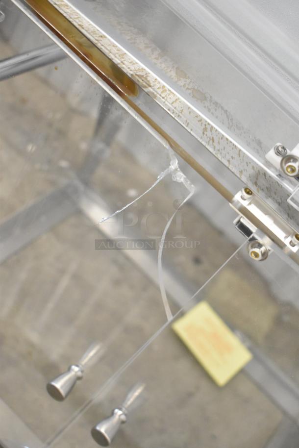Clear poly countertop cabinet with metal handles showing signs of wear and a crack in the glass.