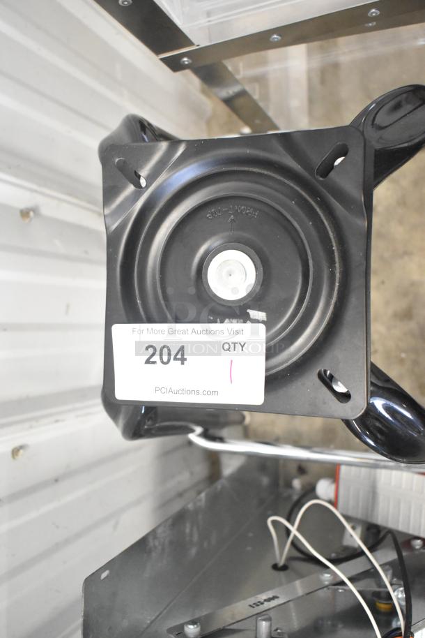 Black bar stool base, metal construction, with label "204 QTY 1" from PCI Auctions. Features mounting holes and swivel mechanism.
