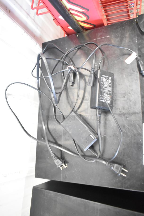 Power cords and chargers on a black surface, likely for Hover-1 Titan HY-TTN hoverboards. Condition appears used.