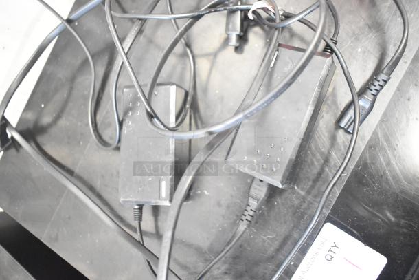 Two black Hover-1 Titan HY-TTN hoverboard chargers with cables, resting on a surface. Auction tag shows "QTY 1".