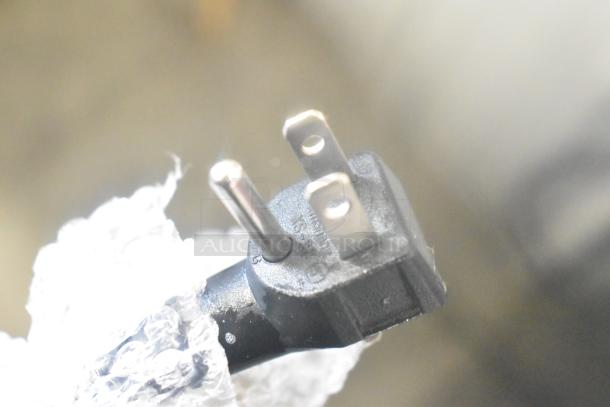 Close-up of an electrical plug partially wrapped in bubble wrap, associated with KoolMore BIM75-BS ice maker.