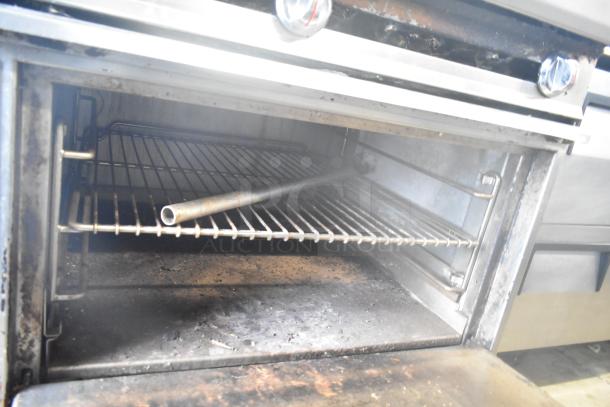 Commercial gas-powered 6 burner range with 2 tier oven, over shelf, backsplash, and commercial casters. Moderate wear.