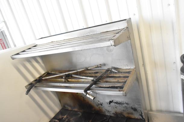 Commercial gas-powered 6 burner range with oven, over shelf, and back splash. Features commercial casters; used condition.