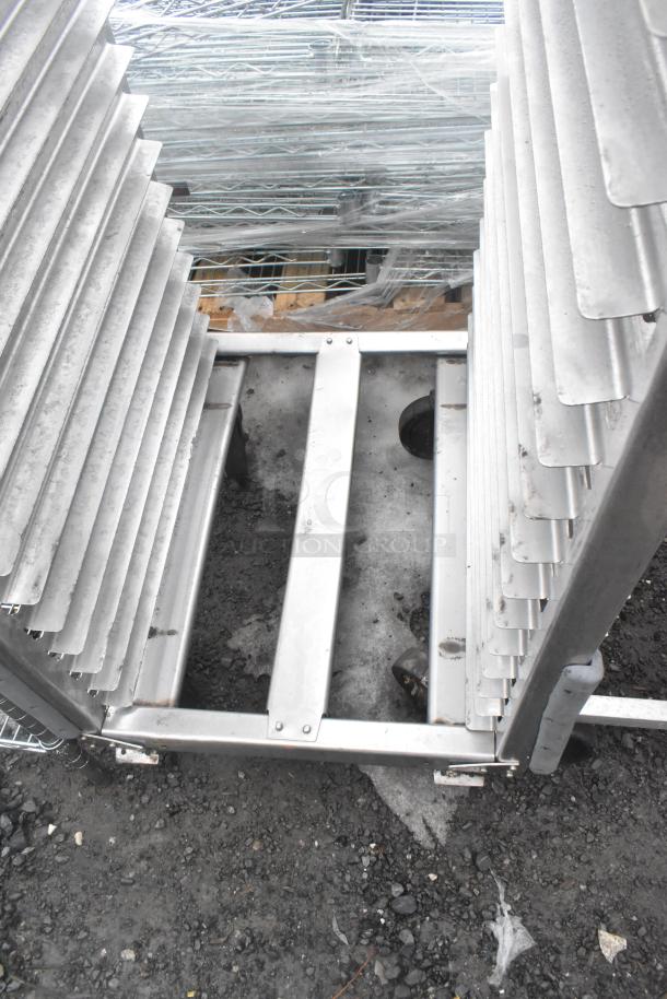 Two commercial pan transport racks on casters, metal, with multiple slotted shelves. Used condition, suitable for kitchen or catering use.