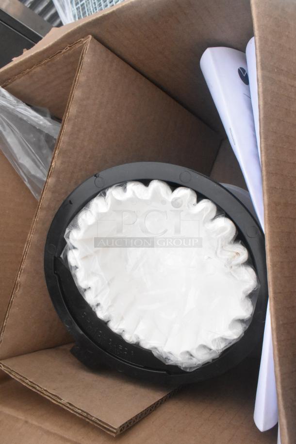 Cardboard box containing coffee filters and manuals.