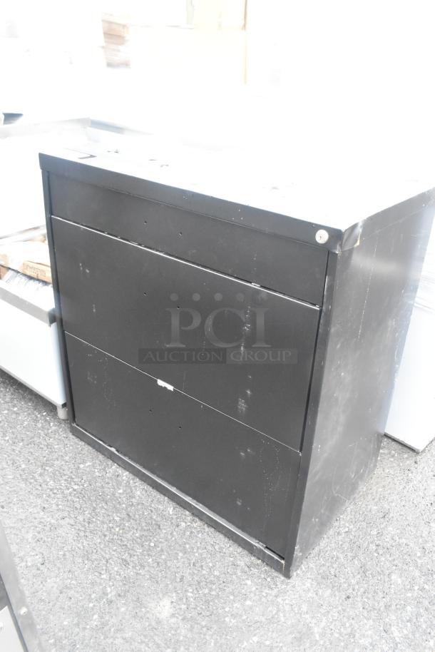 Brand new black 2-drawer filing cabinet with visible scratches and dents, suitable for office storage.