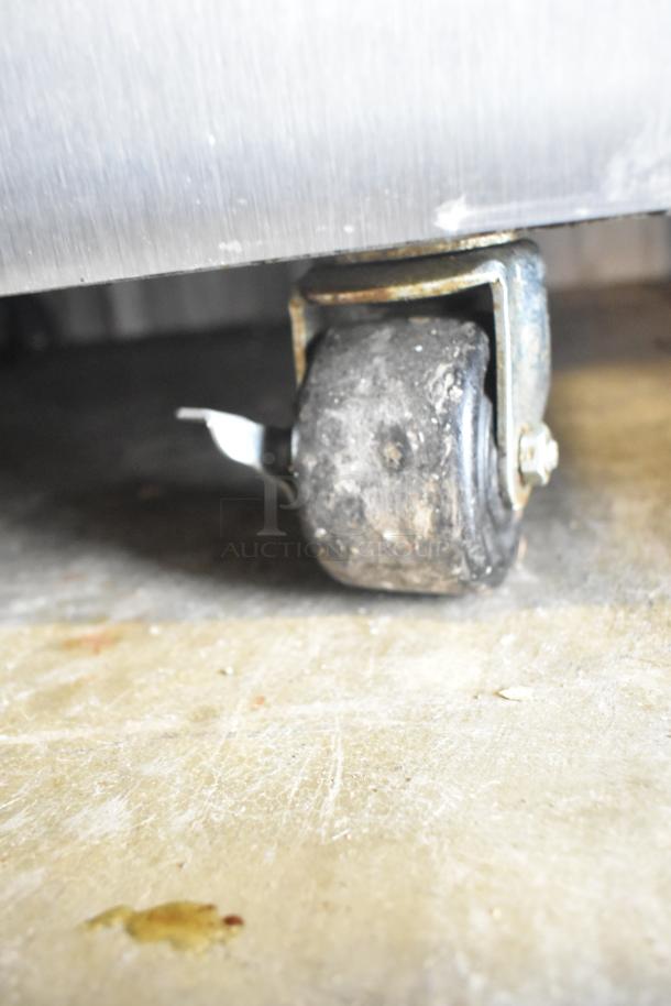 Close-up of a caster wheel from a Taylor C723-27 stainless steel soft serve machine, showing wear and dirt.