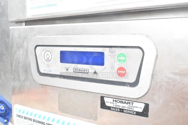 Hobart FT900 commercial dishwasher, flight style, 480V, 3-phase. Control panel with start/stop buttons visible. Good condition.