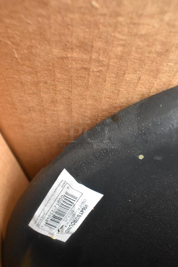 Black item with visible label featuring barcode and text. Slight blemishes on surface, set against brown cardboard.