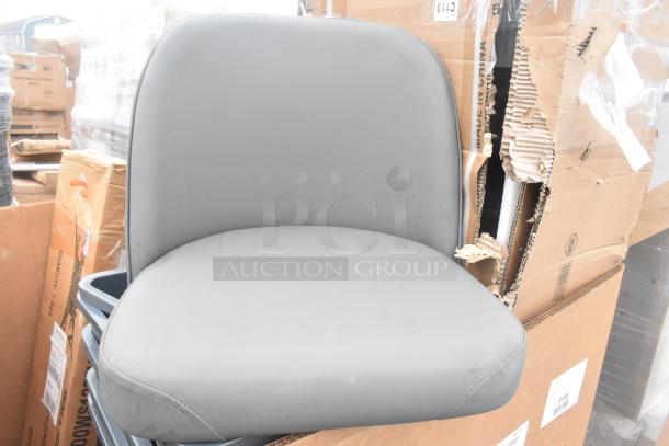 Gray bucket seat, brand new with minor scratches, on top of cardboard boxes. Auction lot includes 14 items total.