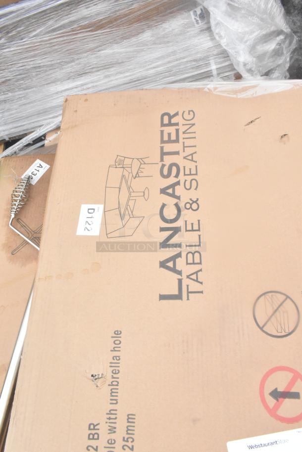 Brown box labeled "Lancaster Table & Seating," contains table with umbrella hole. Condition: new, minor dents. Quantity: 19.