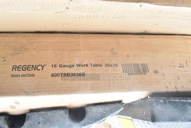 Cardboard box labeled "Regency 16 Gauge Work Table 30x36" model 600TSB3036S, showing scratches and dents.