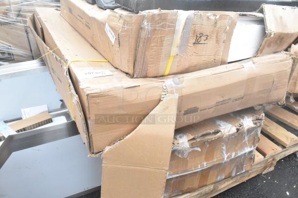 Damaged boxes containing new scratch and dent items, including a wall corner guard, work table, and tray stand, on a pallet.