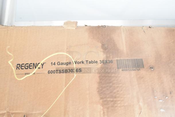 Cardboard box showing Regency 14 Gauge Work Table 30x36 label, slightly worn. Contains new scratch and dent items.