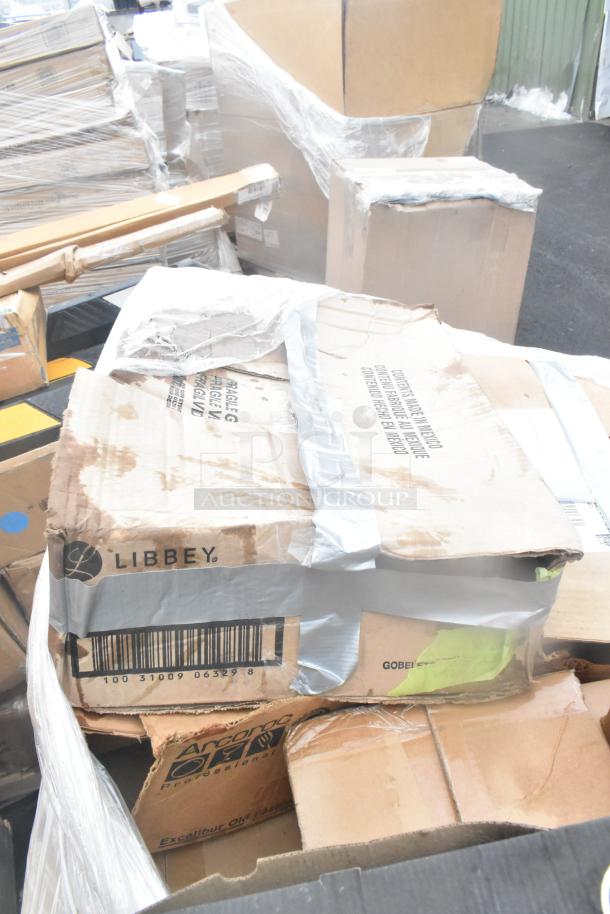 Cardboard boxes labeled "Libbey" and "Arcoroc" are stacked and sealed with tape. Boxes show signs of wear.