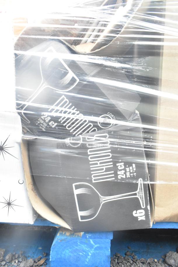 Stacked boxes of glassware and dishes, partially wrapped in plastic. "24 cl" and "x6" visible on boxes. Brand new scratch and dent items.