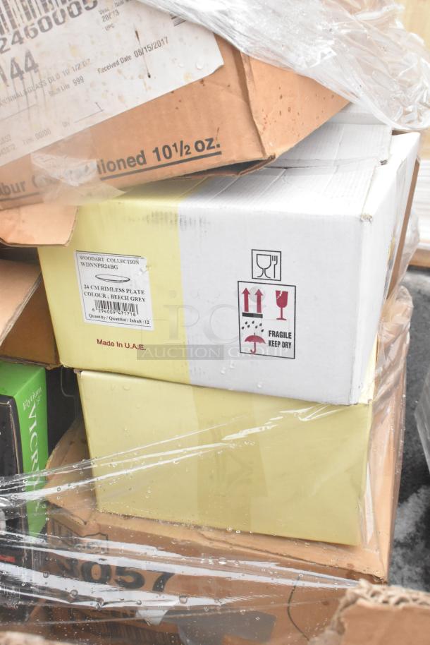 Stacked boxes of glassware and dishes, including Woodart Collection rimless plates, labeled as fragile and made in UAE.