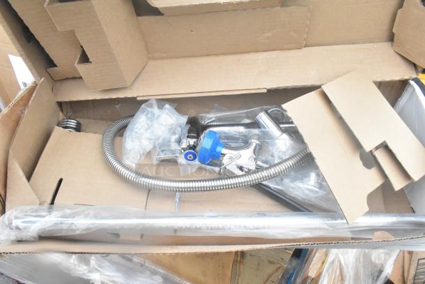 Box containing brand new shelf components with visible metal fittings and hoses, some in plastic bags. Condition: Scratch and dent.