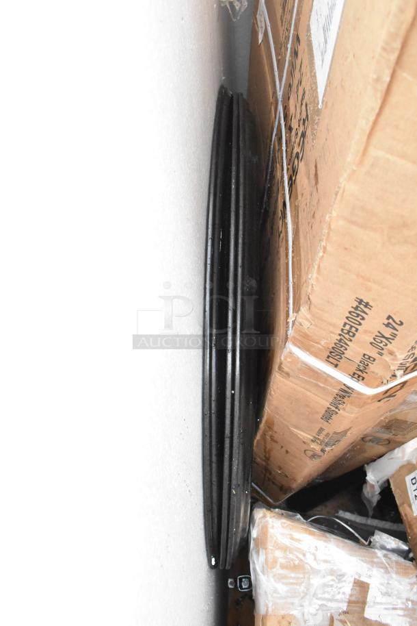 Stacked black metal shelves in original packaging with visible box labels and scratch marks. New condition.