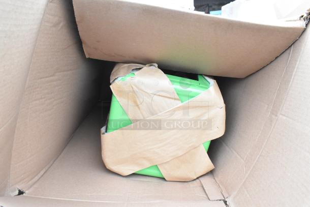 Cardboard box containing green item wrapped in brown paper, part of an auction lot of scratch and dent items, including gloves and cart.