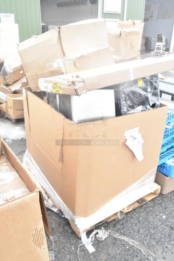 Large cardboard box containing 15 brand new scratch and dent items, including splash guard, flight paddle, ingredient bin, on a pallet.