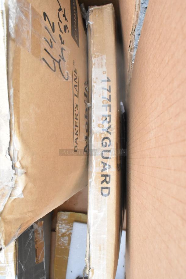 Cardboard boxes labeled with "Baker's Lane" and "1776 FRYGUARD", containing new scratch and dent items like splash guard.