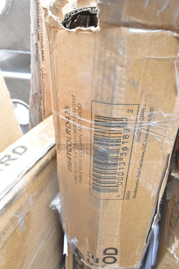 Cardboard boxes containing scratch and dent items. Visible label reads "#164TCLORD25 Standard Height Table Base Column and Rod."