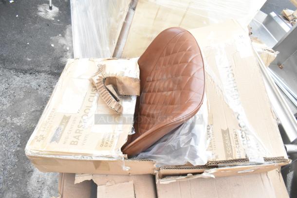 Brown vinyl bar stool cushion in packaging. Minor scratches visible. Box labeled "Lancaster" and "Mid-Century," with damage.
