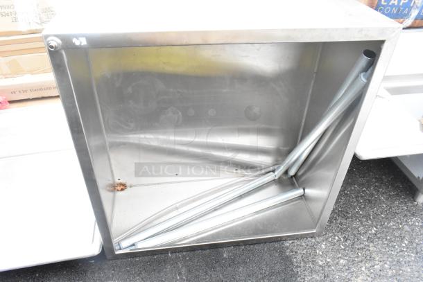 Brand new metal bin with visible dents and scratches, includes metal poles inside, showing minor rust spot on bottom corner.