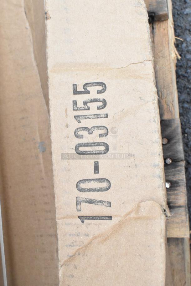 Cardboard box with printed code "170-03155," part of a scratch and dent auction lot including a sink, shelving posts, and outdoor table.